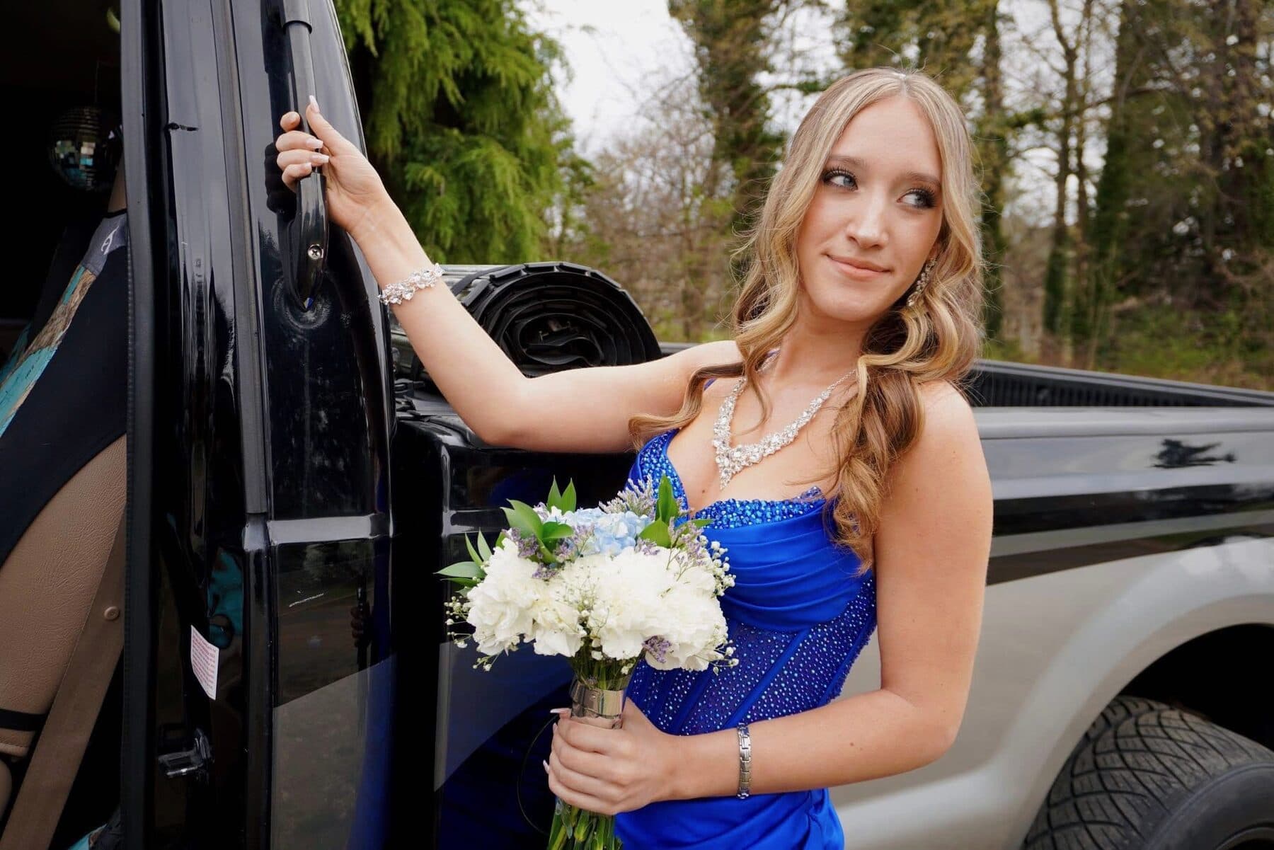 Stepping out of a black truck in a blue gown