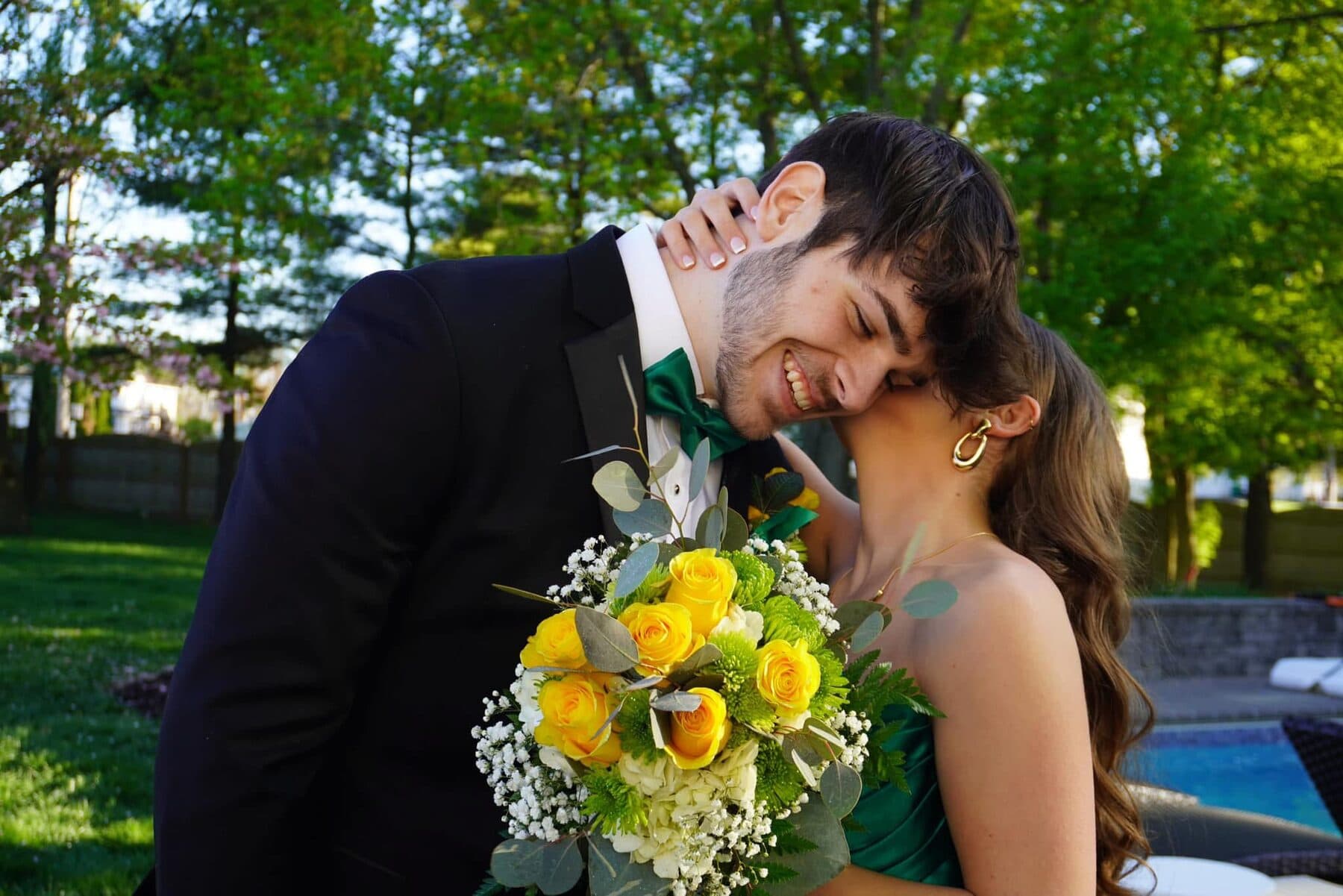 A couple kissing behind a yellow-rose bouquet