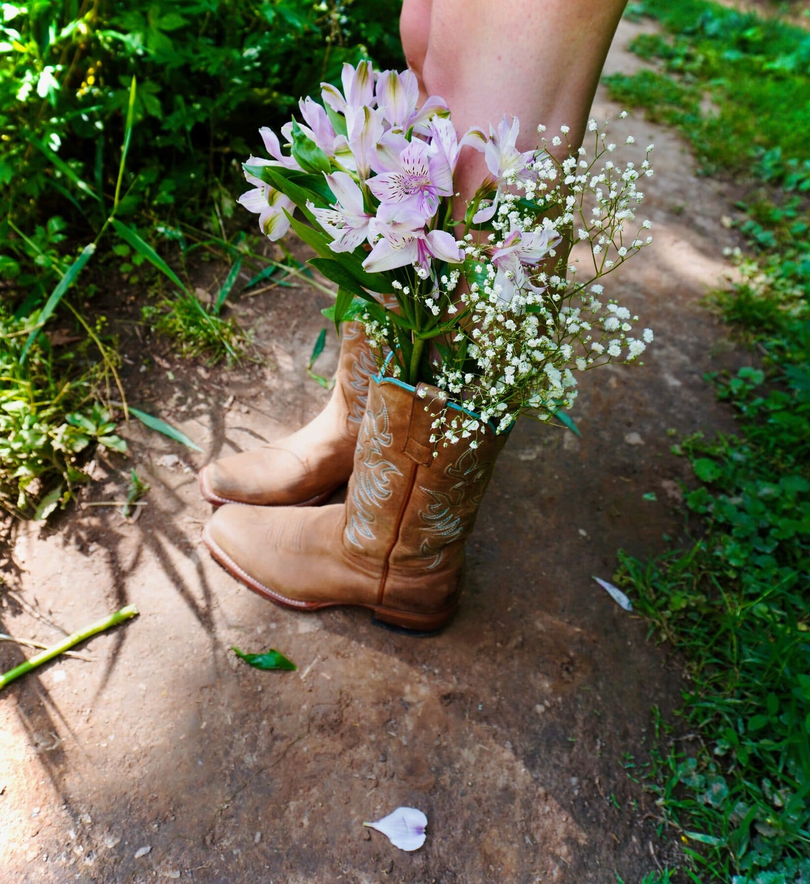 Cowboy boots filled with wildflowers on a path