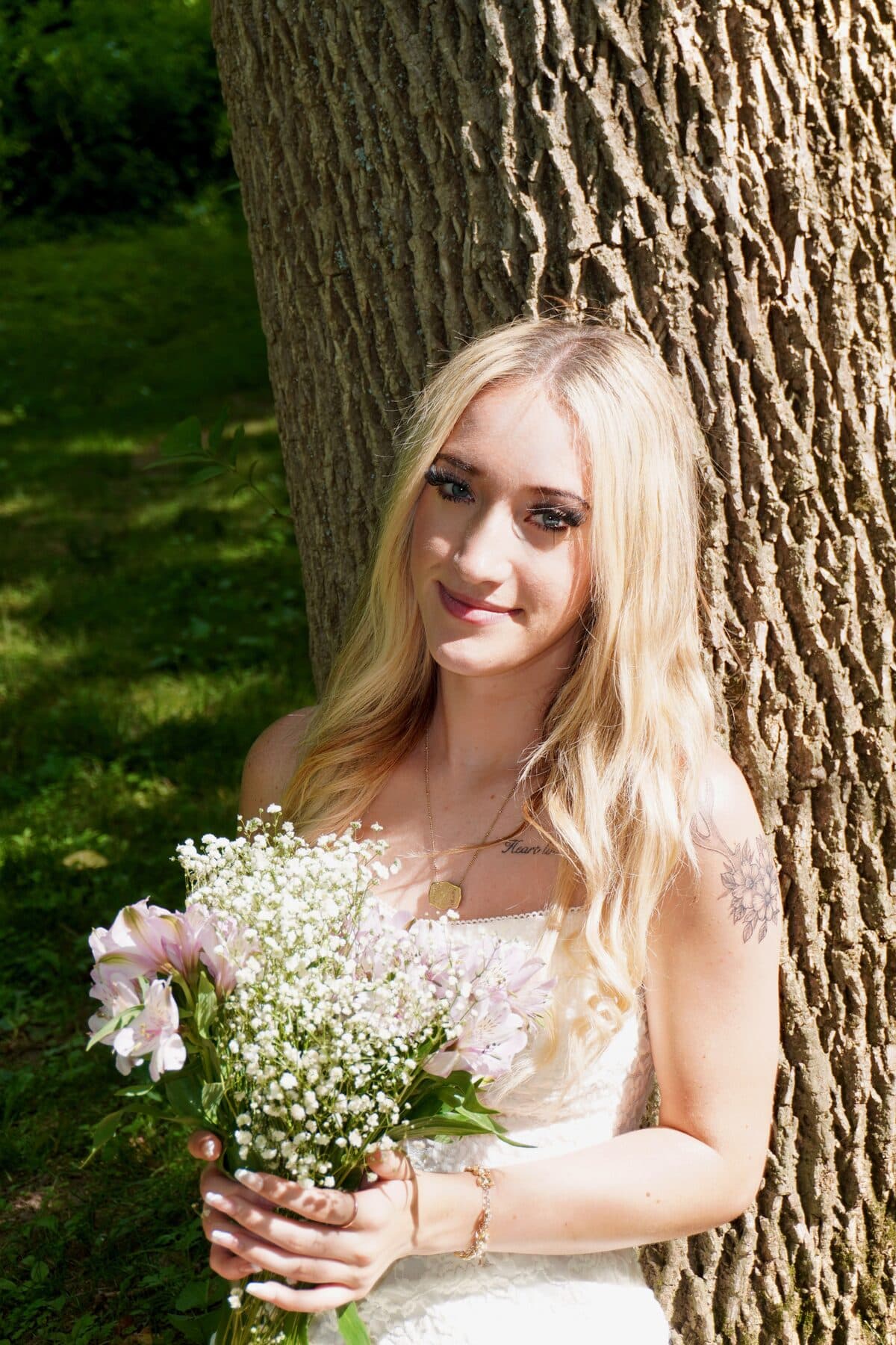 Leaning against a tree trunk with a bouquet